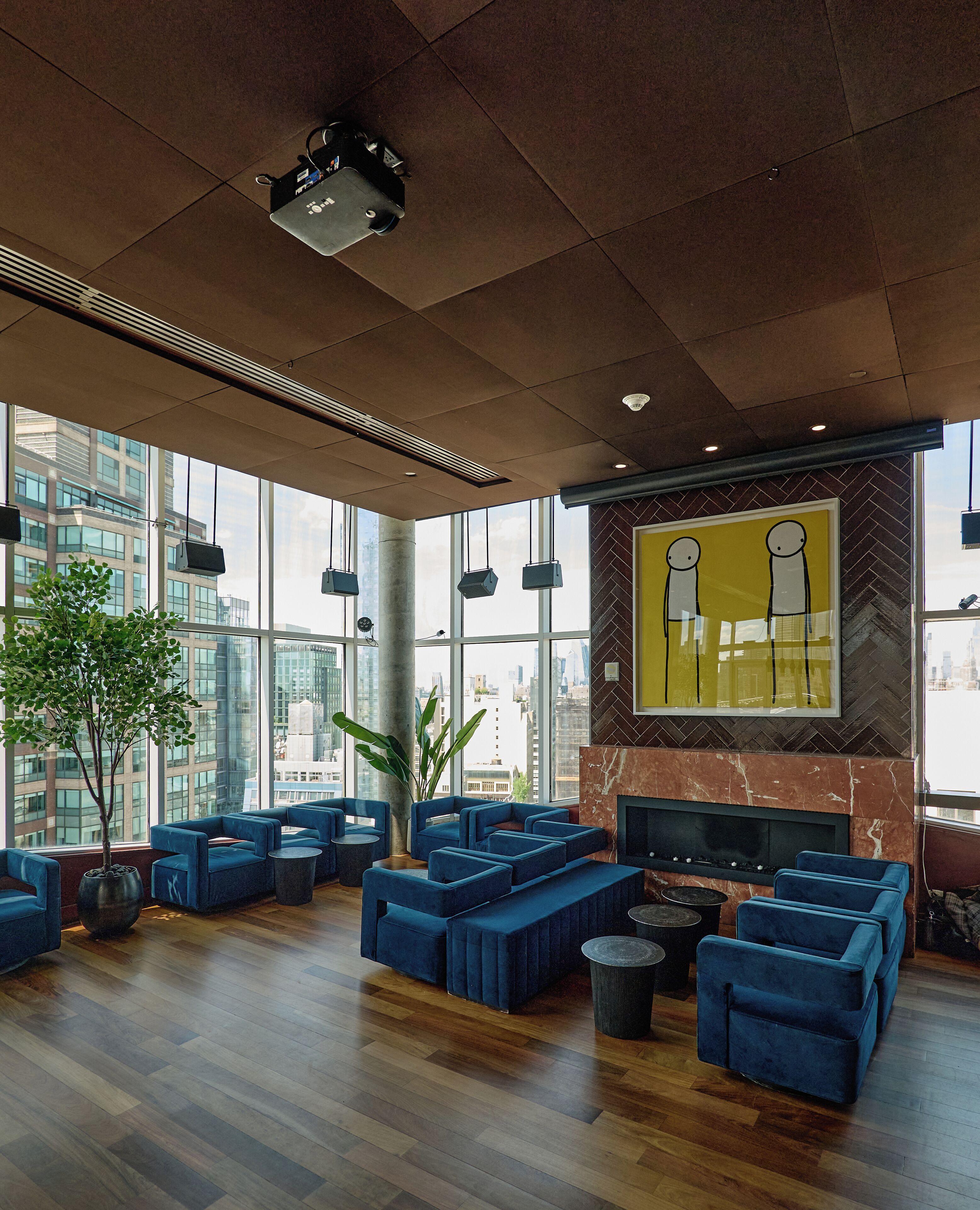 A spacious lobby with a modern design, featuring a large seating area, a fireplace, and a large window offering a city view.