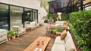 Un patio al aire libre con mobiliario de mimbre, una mesa de madera y plantas en macetas.