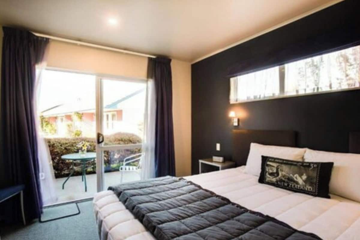 Habitación de hotel con cama, una mesita, una silla y vistas al exterior.