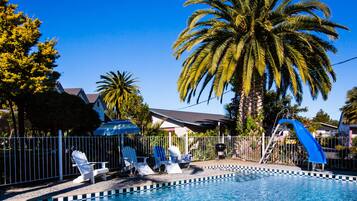 Relax by the pool surrounded by lounge chairs and a fun blue slide for kids.