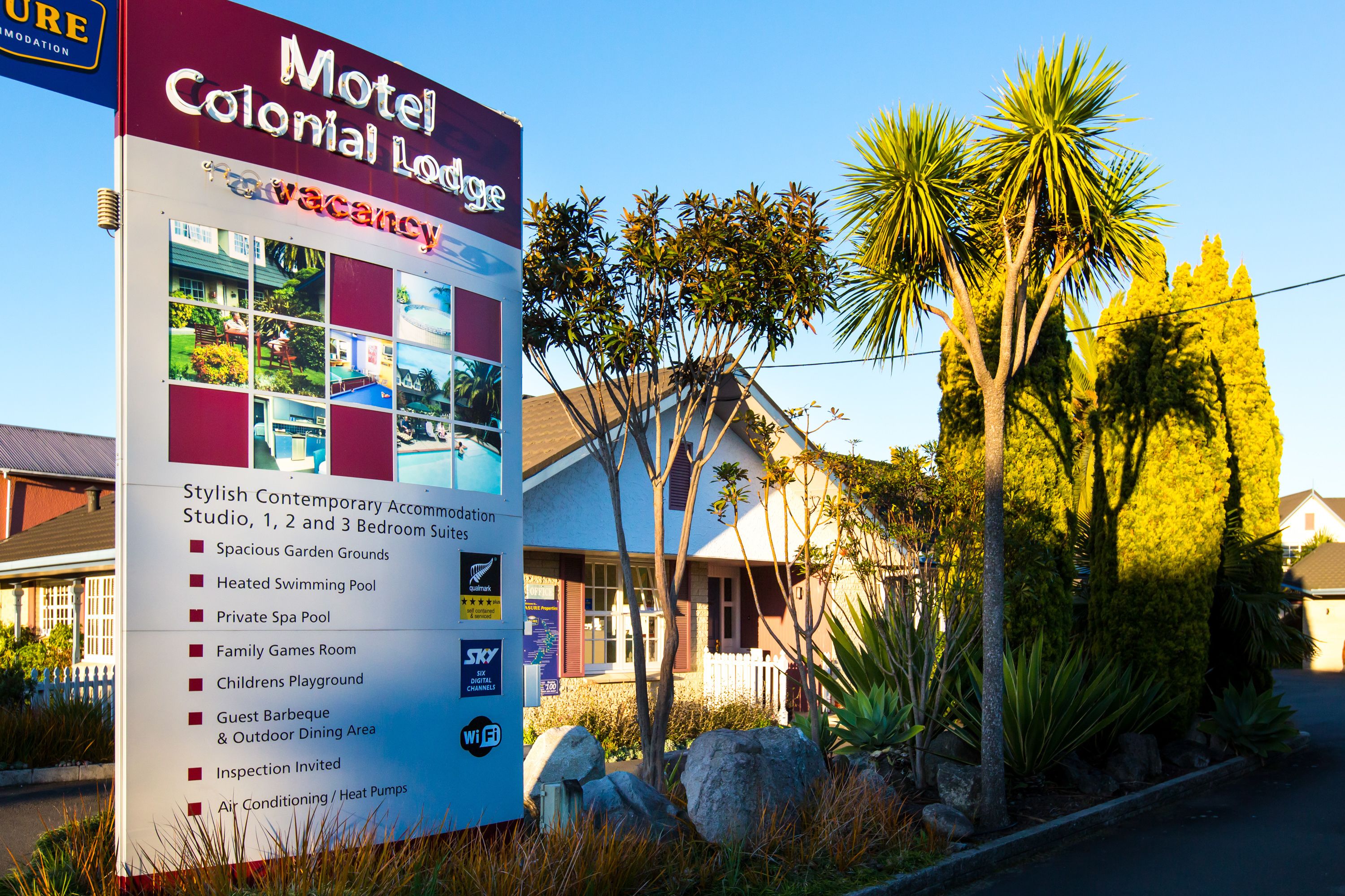 A motel sign with amenities including spacious garden grounds, heated swimming pool, private spa pool, family games room, childrens playground, guest barbeque, outdoor dining area, and air conditioning/heat pumps.