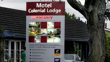 A motel sign with a list of amenities including spacious garden grounds, heated swimming pool, private spa pool, family games room, playground, guest barbecue, and outdoor dining area.