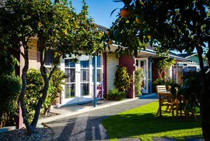 Ein Haus mit Vordergarten, einem Essbereich mit Tisch und Stühlen sowie einer großen Topfpflanze.
