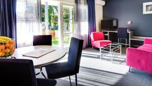 Una habitación de hotel moderna con una mesa redonda, dos sillas, un televisor y un sofá.