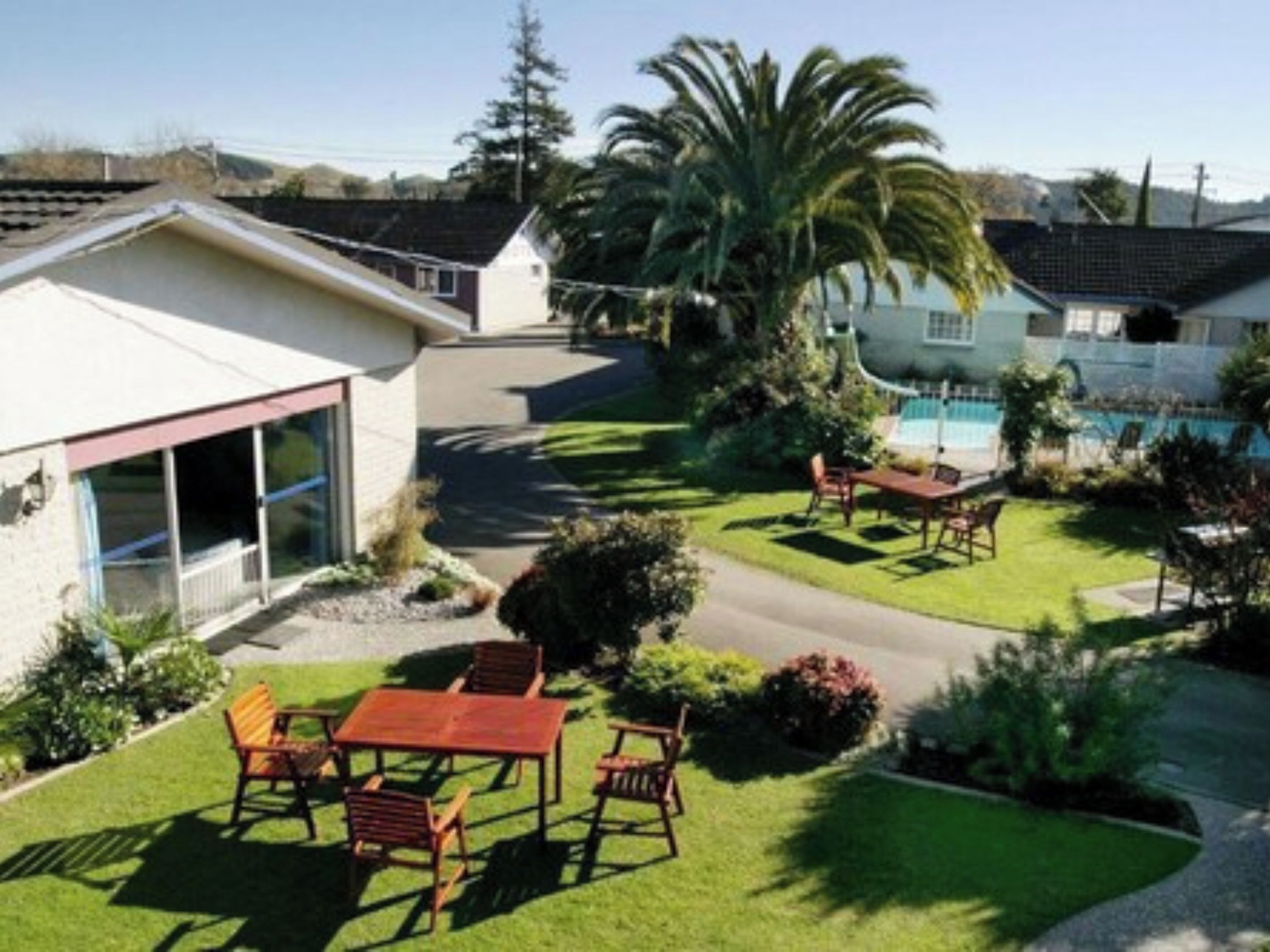 Una propiedad residencial con un patio, piscina y césped bien cuidado.