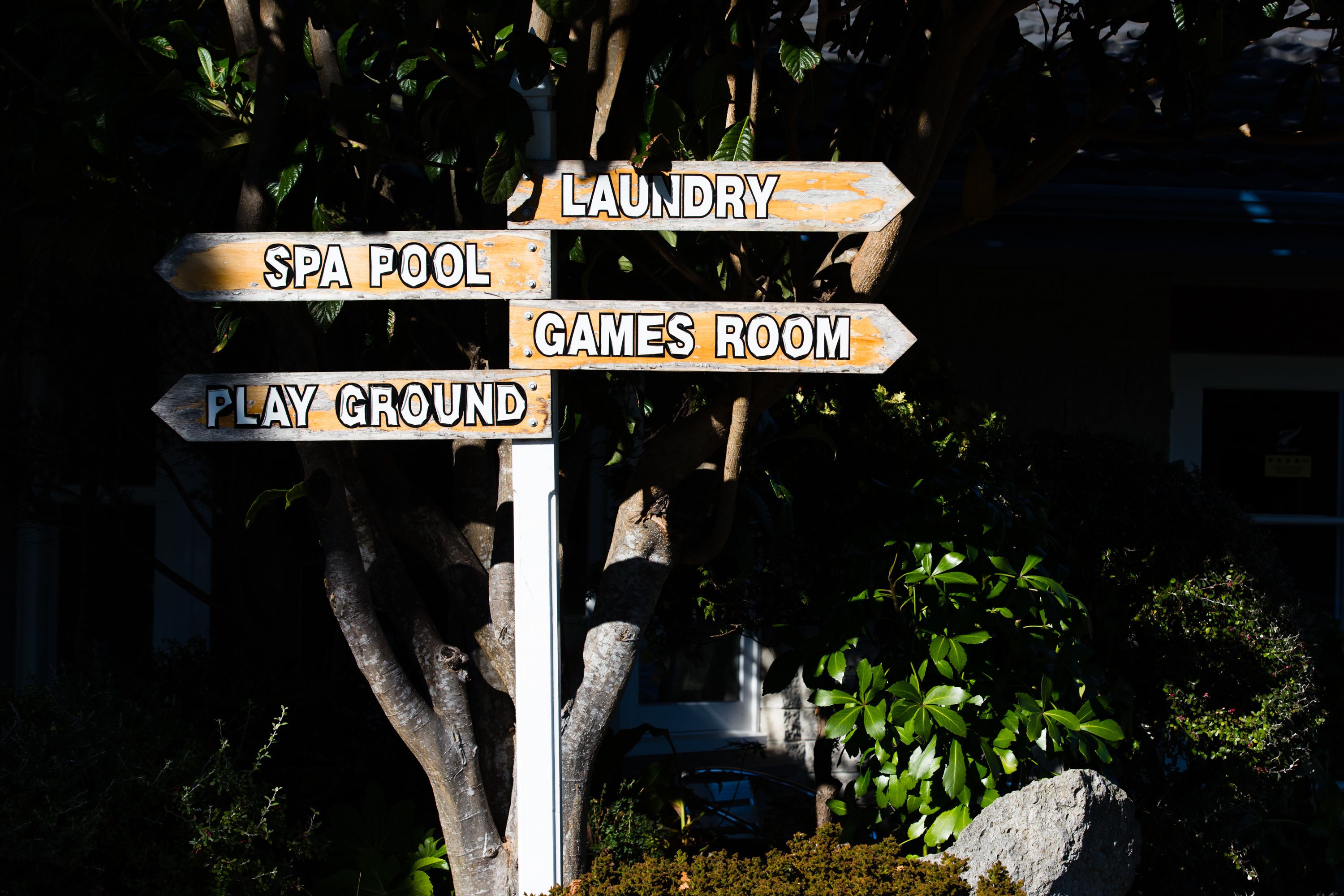 A directional signpost with arrows pointing to amenities such as laundry, spa pool, games room, and playground.