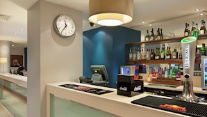 Ein Hotel-Rezeptionsbereich mit einer Uhr, einer Bar und verschiedenen Spirituosenflaschen.