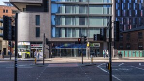 A modern building with a Holiday Inn Express sign, a Spar store, and a traffic light at an intersection. - Holiday Inn Express Manchester CC - Oxford Road by IHG (Manchester)