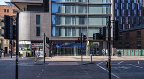 A modern building with a Holiday Inn Express sign, a Spar store, and a traffic light at an intersection.