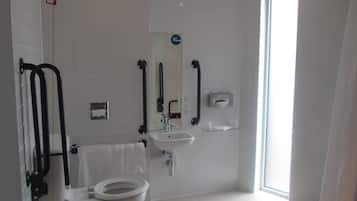 Un baño moderno con inodoro, lavamanos y barras de apoyo.