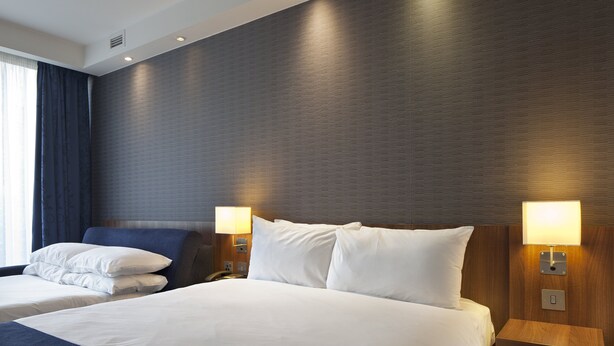 A hotel room with a large bed, two bedside tables with lamps, a headboard, and a window with curtains. - Holiday Inn Express Manchester CC - Oxford Road by IHG (Manchester)