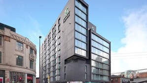A modern hotel with a prominent 'Express' sign, featuring a corner location with a curved facade and multiple windows. - Holiday Inn Express Manchester CC - Oxford Road by IHG (Manchester)