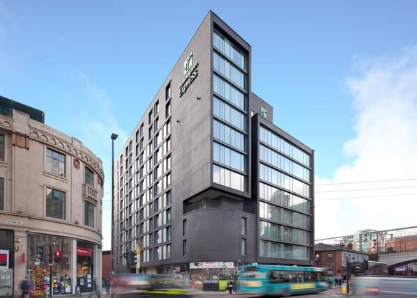 A modern hotel with a prominent 'Express' sign, featuring a corner location with a curved facade and multiple windows.