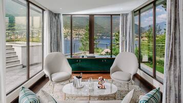 A modern room with a large window, two white chairs, a round coffee table, and a green cabinet.