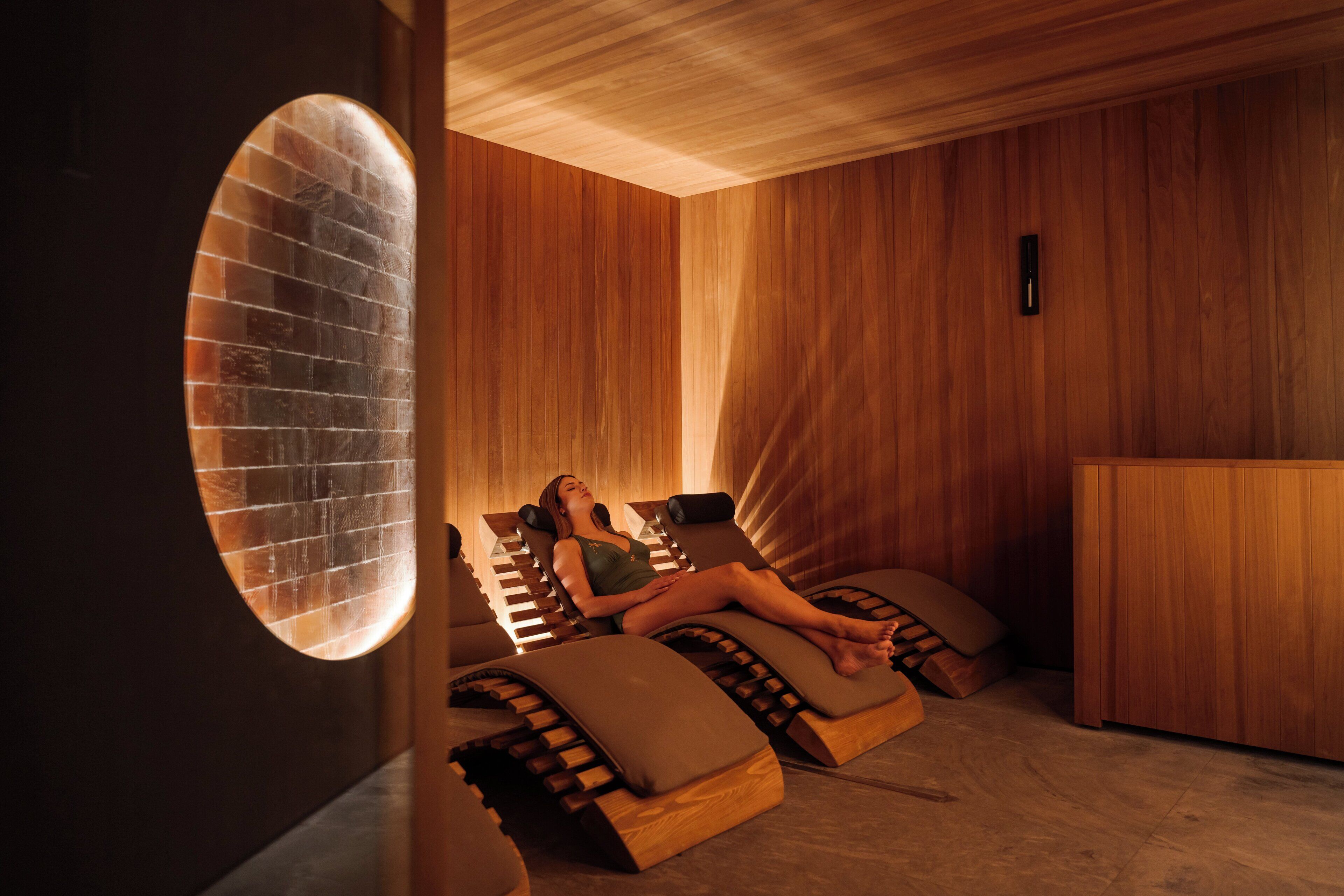 Una sauna con pareti in legno e un'ampia finestra ovale.