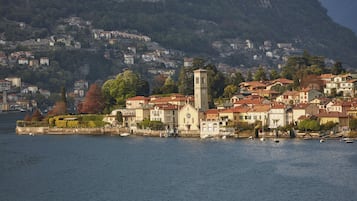 Un pueblo costero con una imponente torre de iglesia, edificios frente al mar y colinas al fondo.