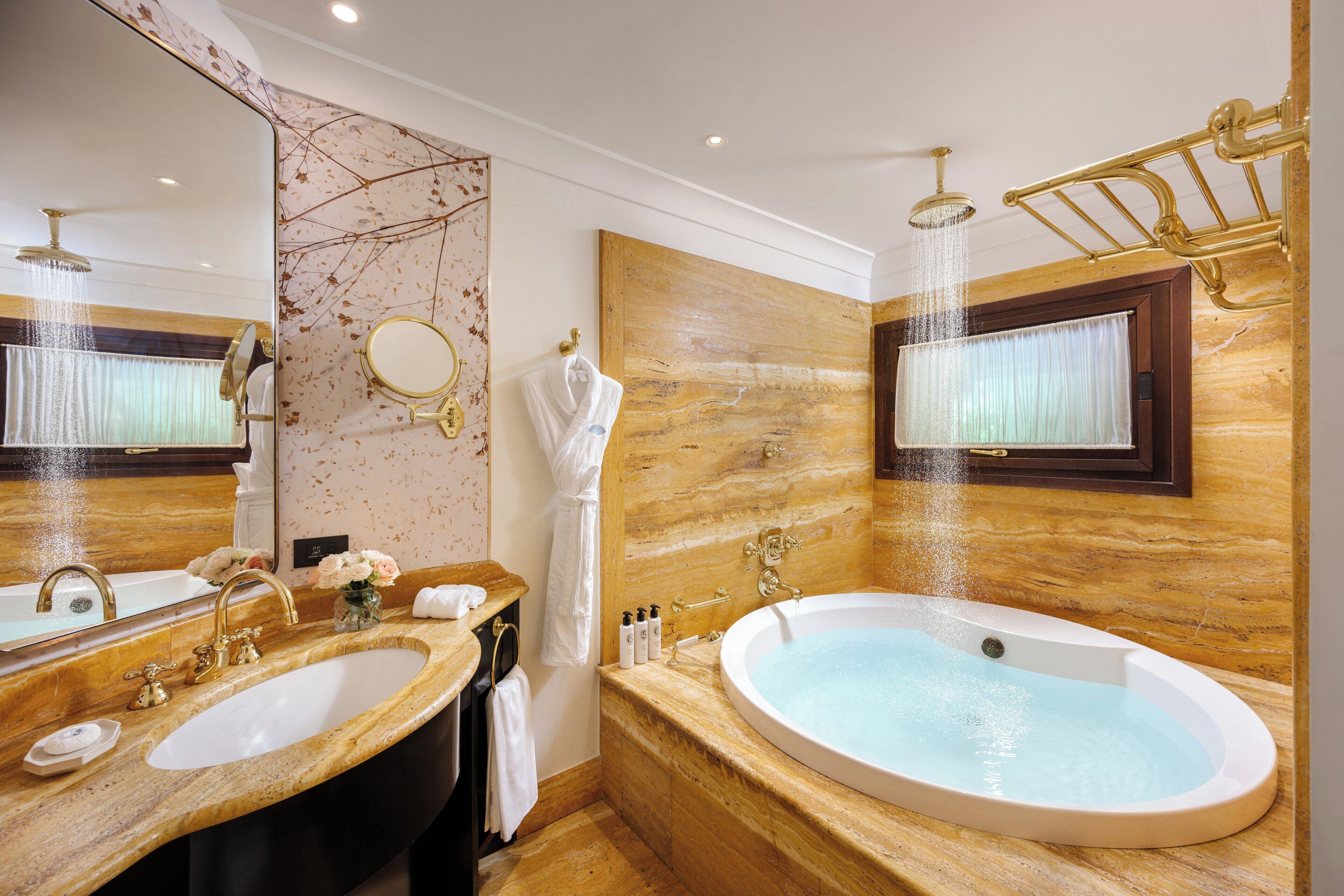Ein luxuriöses Badezimmer mit einer großen Badewanne, zwei Waschbecken, einem Schminktisch und einem großen Spiegel.