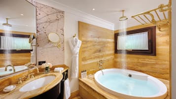Ein luxuriöses Badezimmer mit einer großen Badewanne, zwei Waschbecken, einem Schminktisch und einem großen Spiegel.