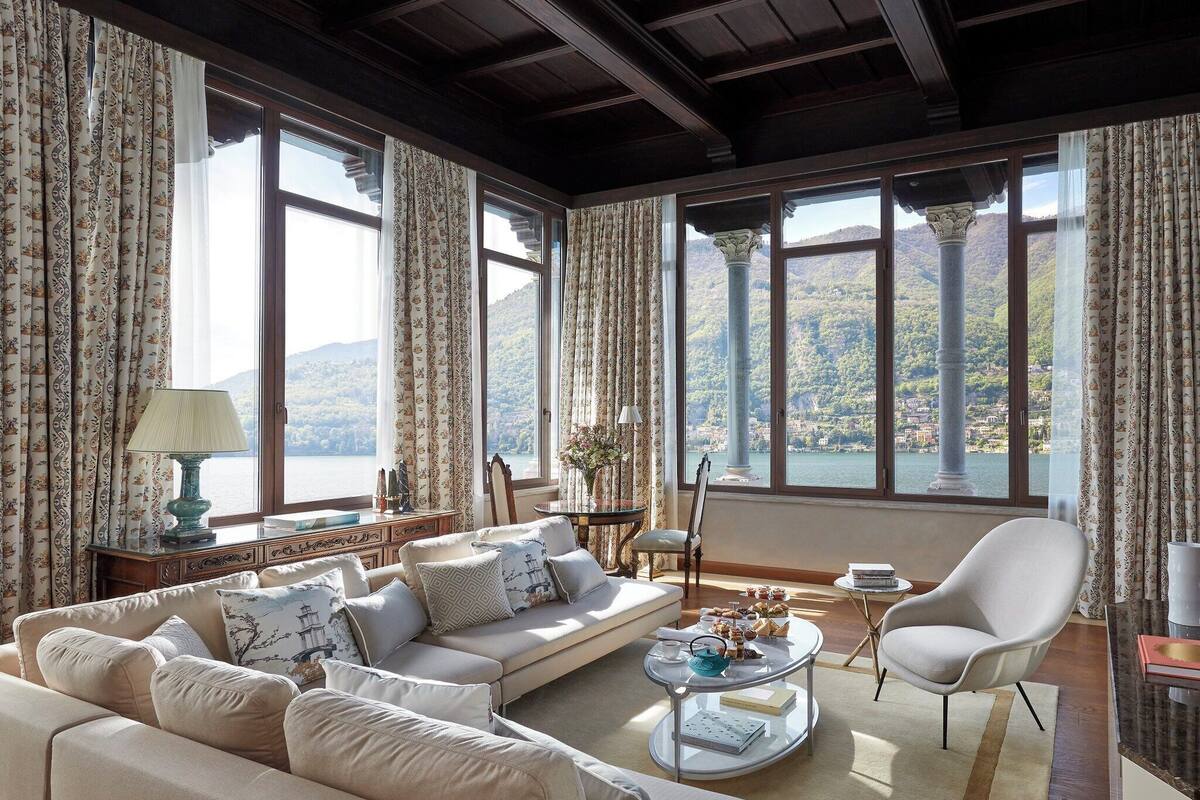 A spacious living room with a sofa set, a coffee table, and a view of a mountainous landscape through large windows.