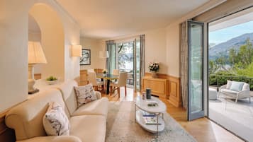 Una sala de estar moderna con sofá, una mesa de centro y comedor. Incluye un balcón con asientos exteriores y vistas a las montañas.