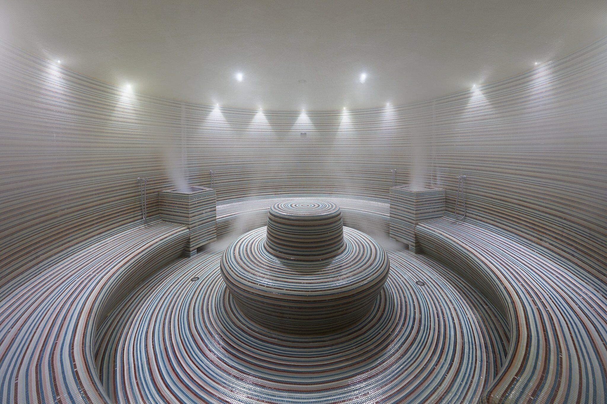 A circular room with a central spiral staircase and seating areas along the walls.