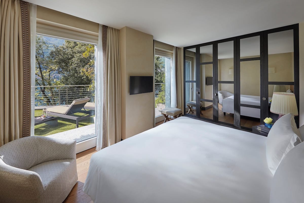 Una habitación de hotel con una cama grande, un sofá, un televisor y un balcón con piscina.