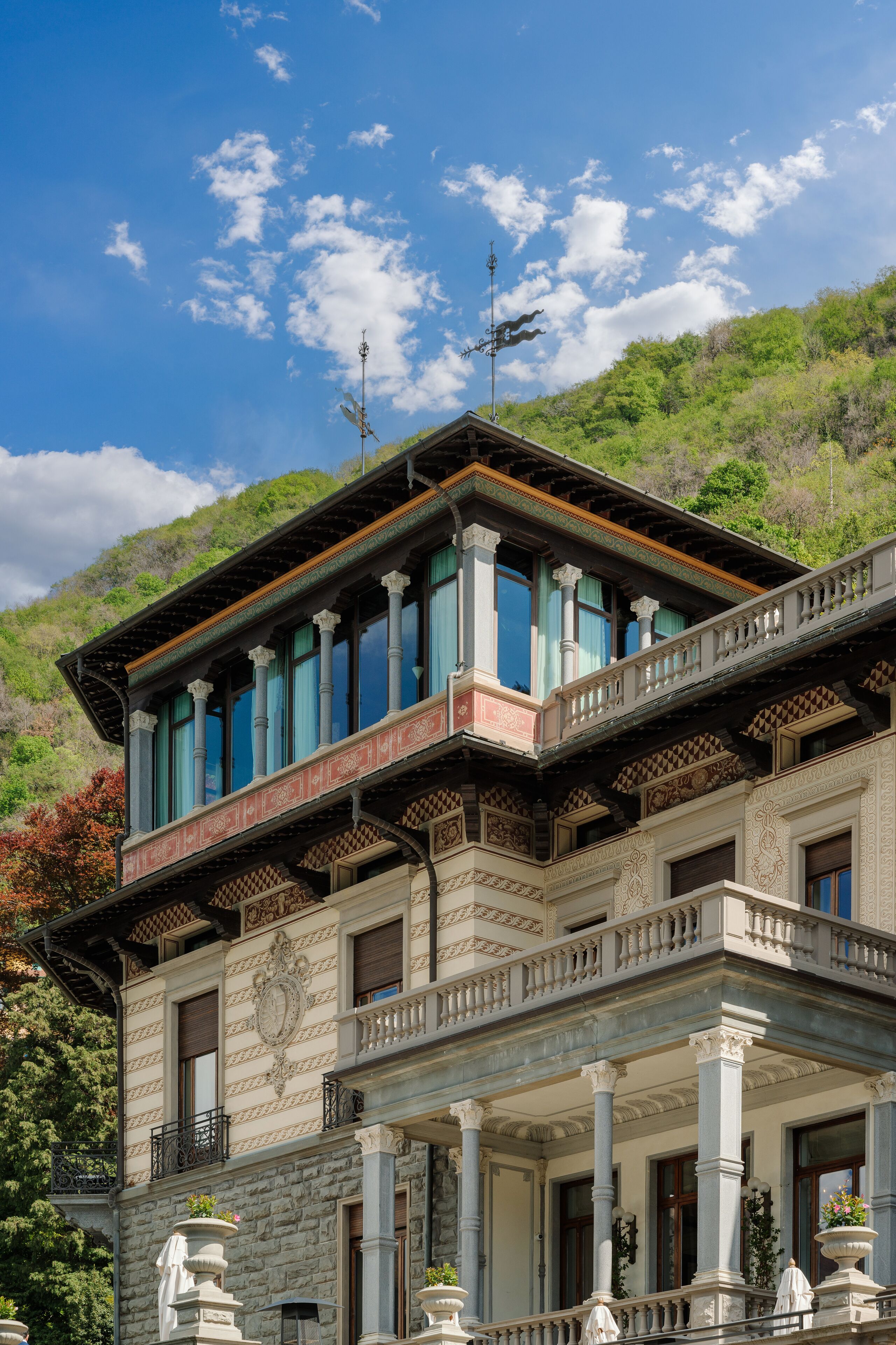Un edificio histórico con un balcón, columnas y un telón de fondo montañoso.