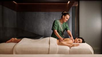 Una sesión de masoterapia en un spa, con una sala de tonos oscuros y una camilla de masaje.