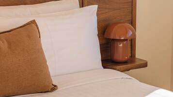 Una cama bien hecha con cabecera de madera, almohada marrón y lámpara de noche.