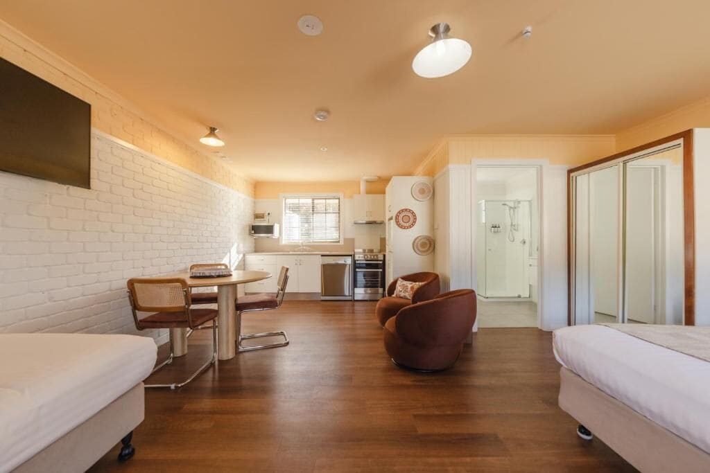 A compact living space with a kitchenette, a dining area, and a shower.