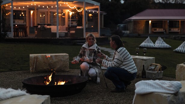 An outdoor seating area with a fire pit, stone seating, and a covered structure with string lights. - Amadiya Port Arthur Villas (Port Arthur)