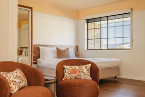 A bedroom with a bed, two chairs, a small table, and a window with a view. - Amadiya Port Arthur Villas (Port Arthur)