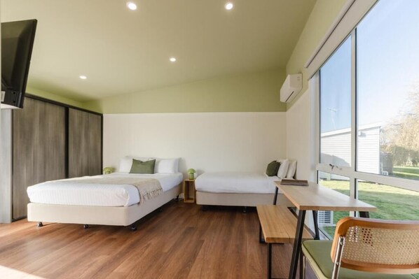 A modern room with two beds, a dining table, and a chair. - Amadiya Port Arthur Villas (Port Arthur)