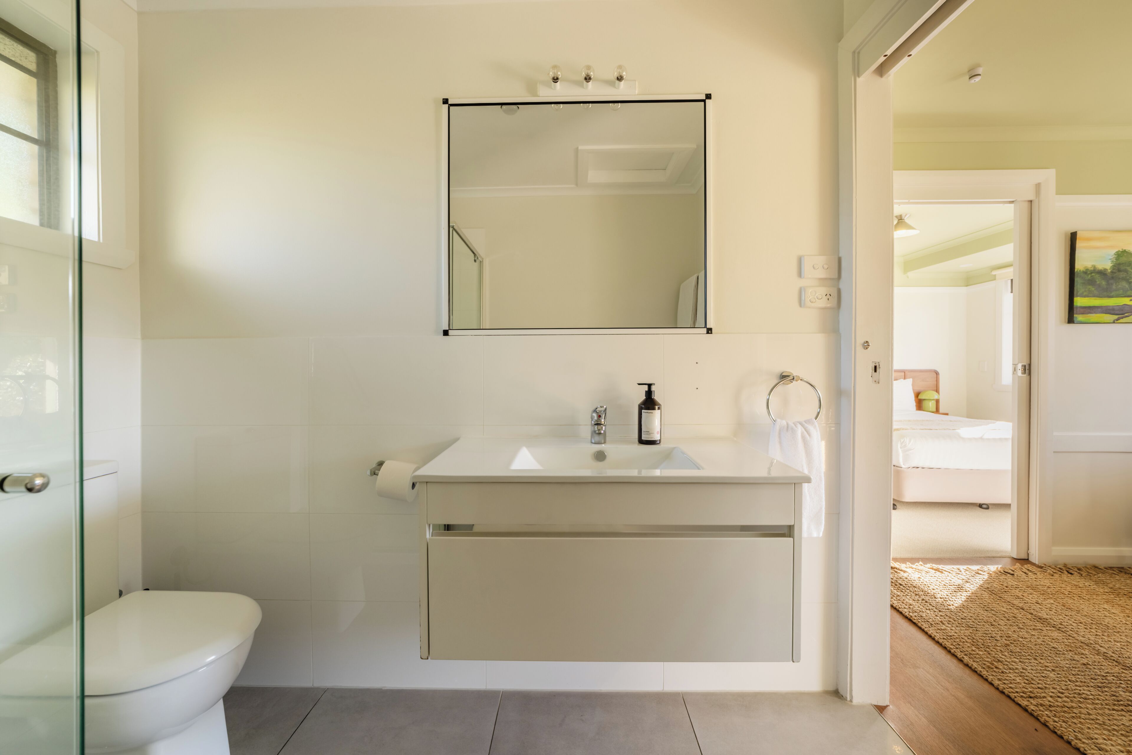 Un bagno con toilette, lavandino, specchio e zona doccia.