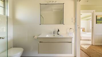 Un baño con inodoro, lavabo, espejo y cabina de ducha.