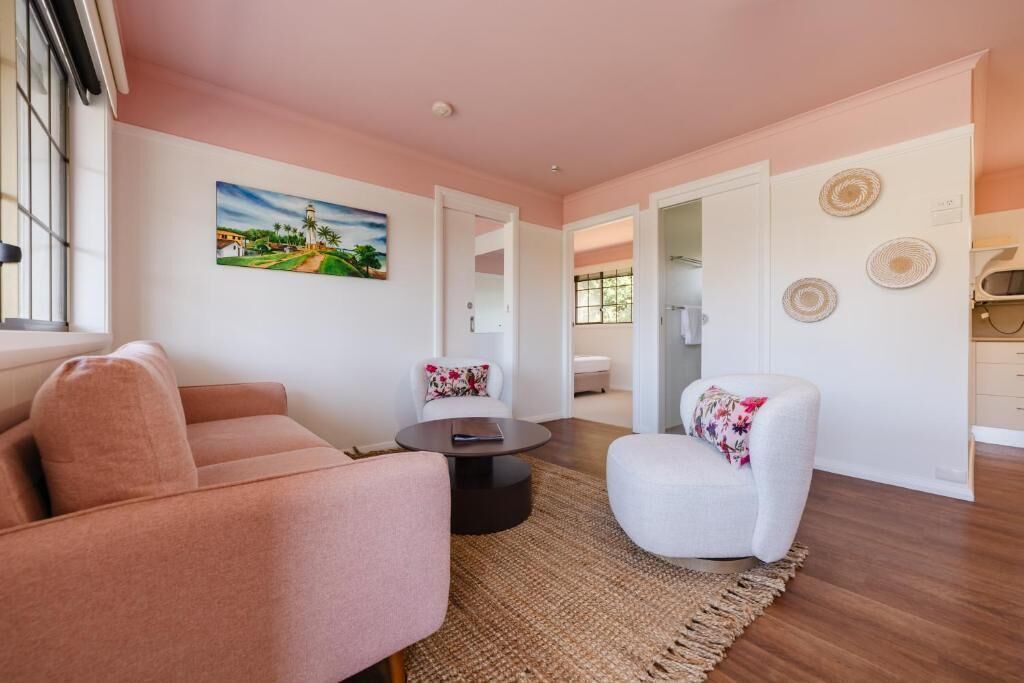A living room with a sofa, armchair, coffee table, and a painting on the wall.
