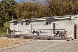 A row of single-story mobile homes with a covered outdoor area and tables. - Amadiya Port Arthur Villas (Port Arthur)
