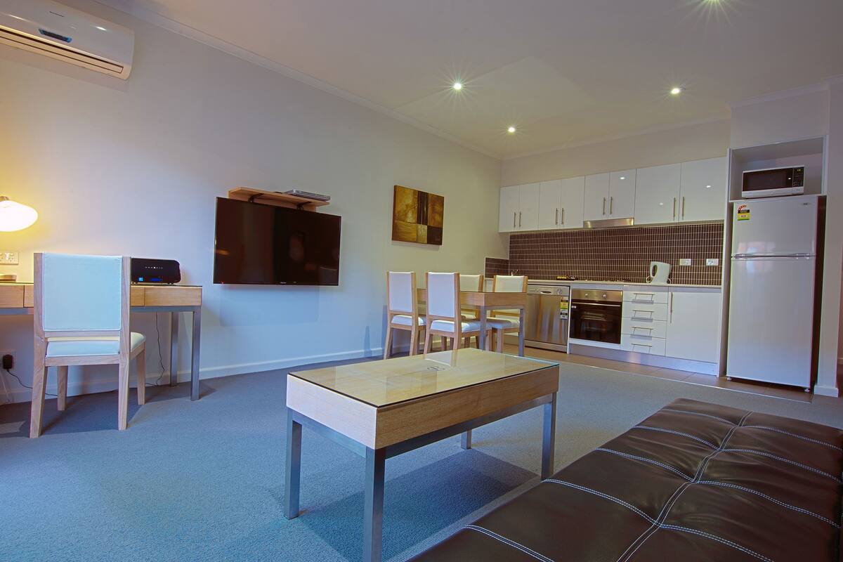 A modern kitchen with white cabinets, a microwave, and a refrigerator.