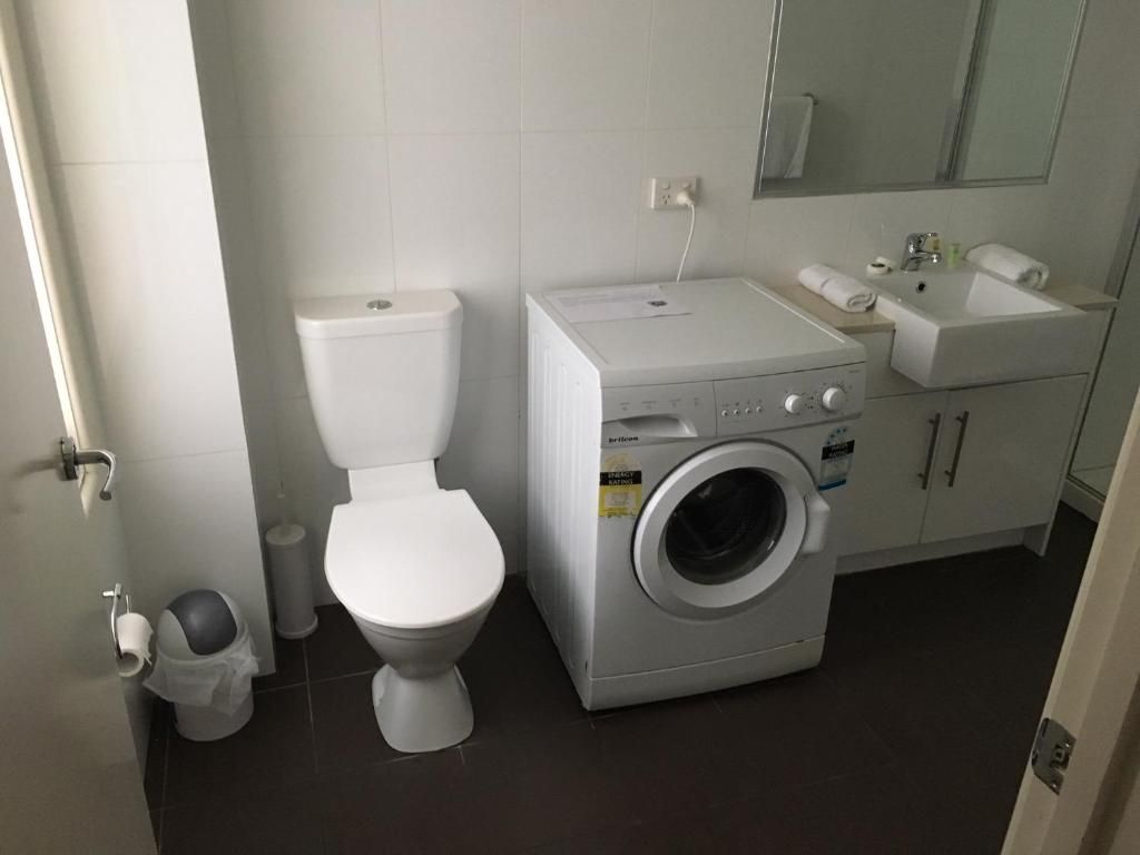 A bathroom with a toilet, washing machine, and sink.