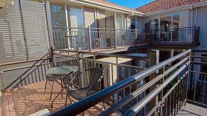 A balcony with metal railings, a table, and two chairs. - Brighton Serviced Apartments (Brighton)