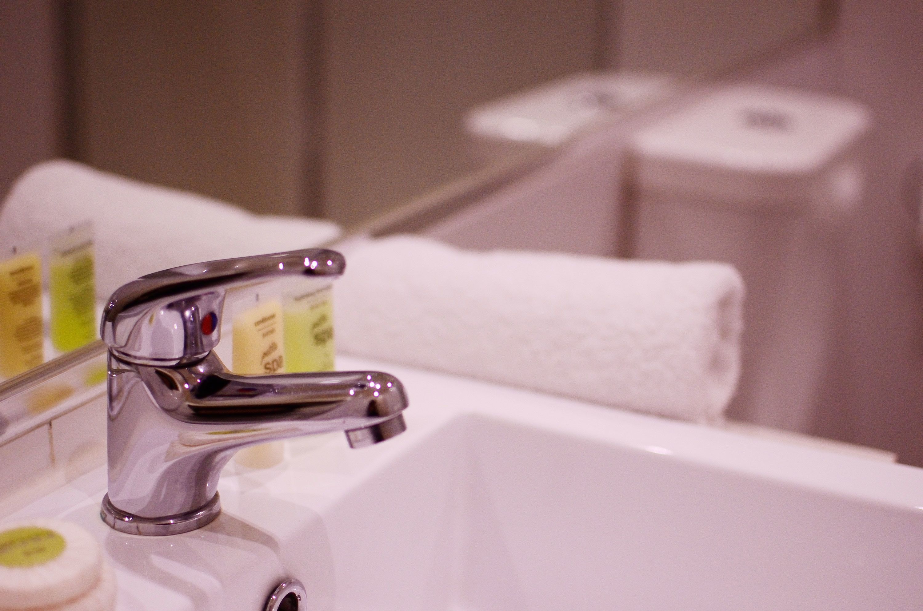 A bathroom sink with a chrome faucet, a white towel, and a soap dispenser.