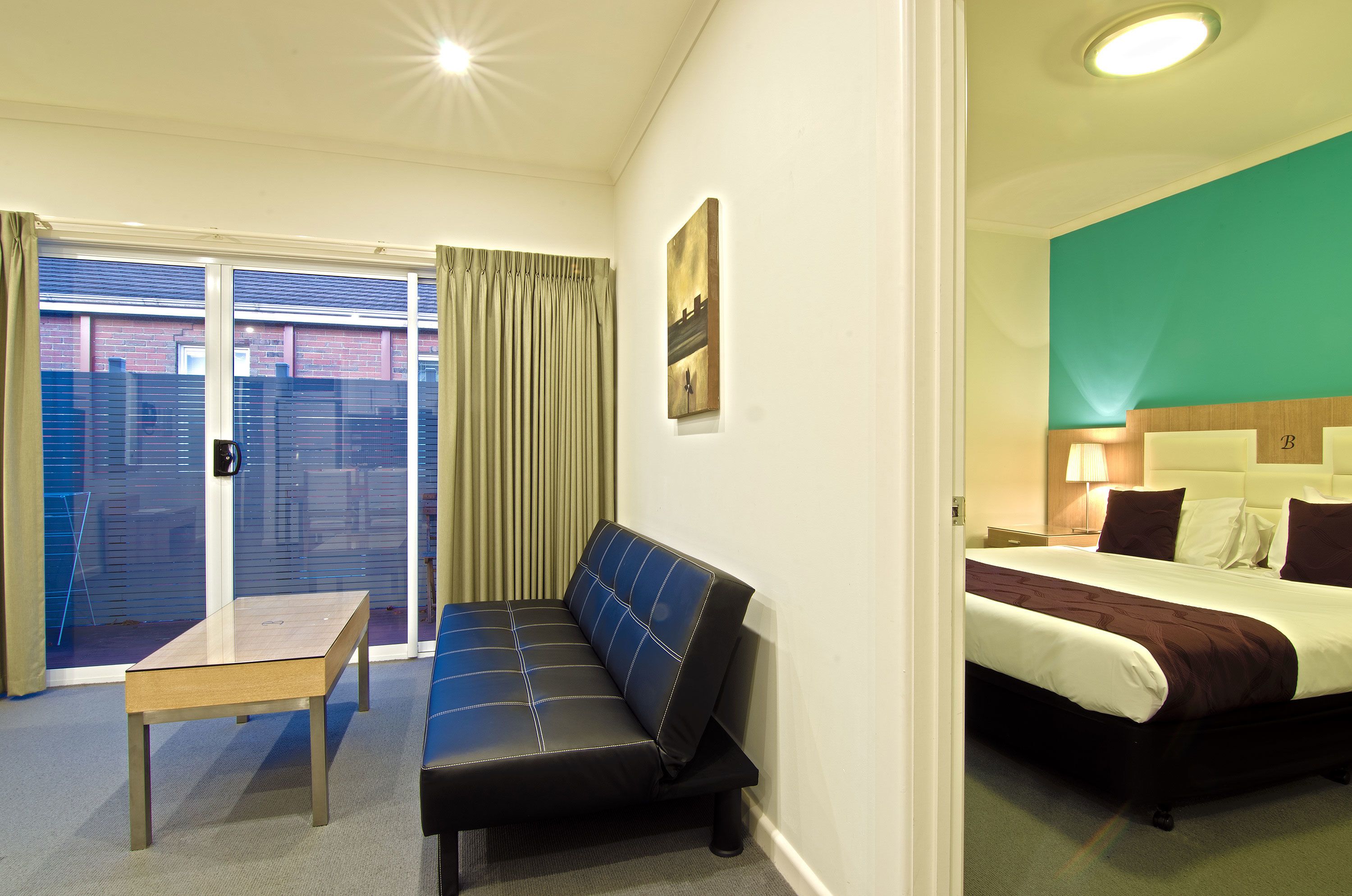Habitación de hotel con cama, sofá, una mesita y vista a un edificio a través de la ventana.