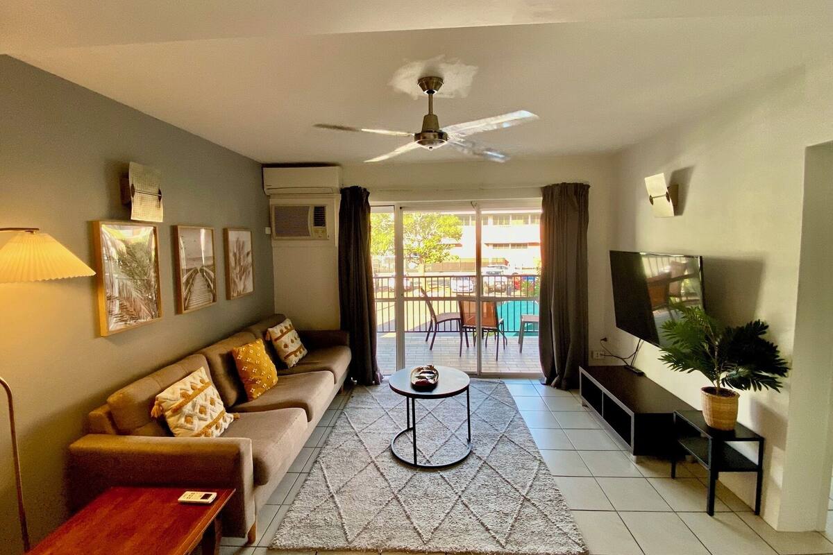 A living room with a sofa, a coffee table, a TV, and a ceiling fan.