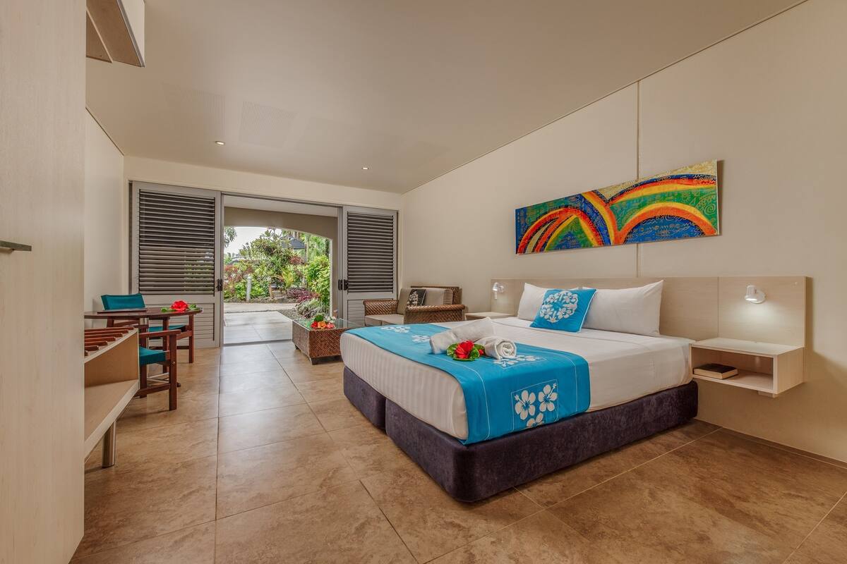 A modern hotel room with a large bed, a desk, and a view of the outdoors.