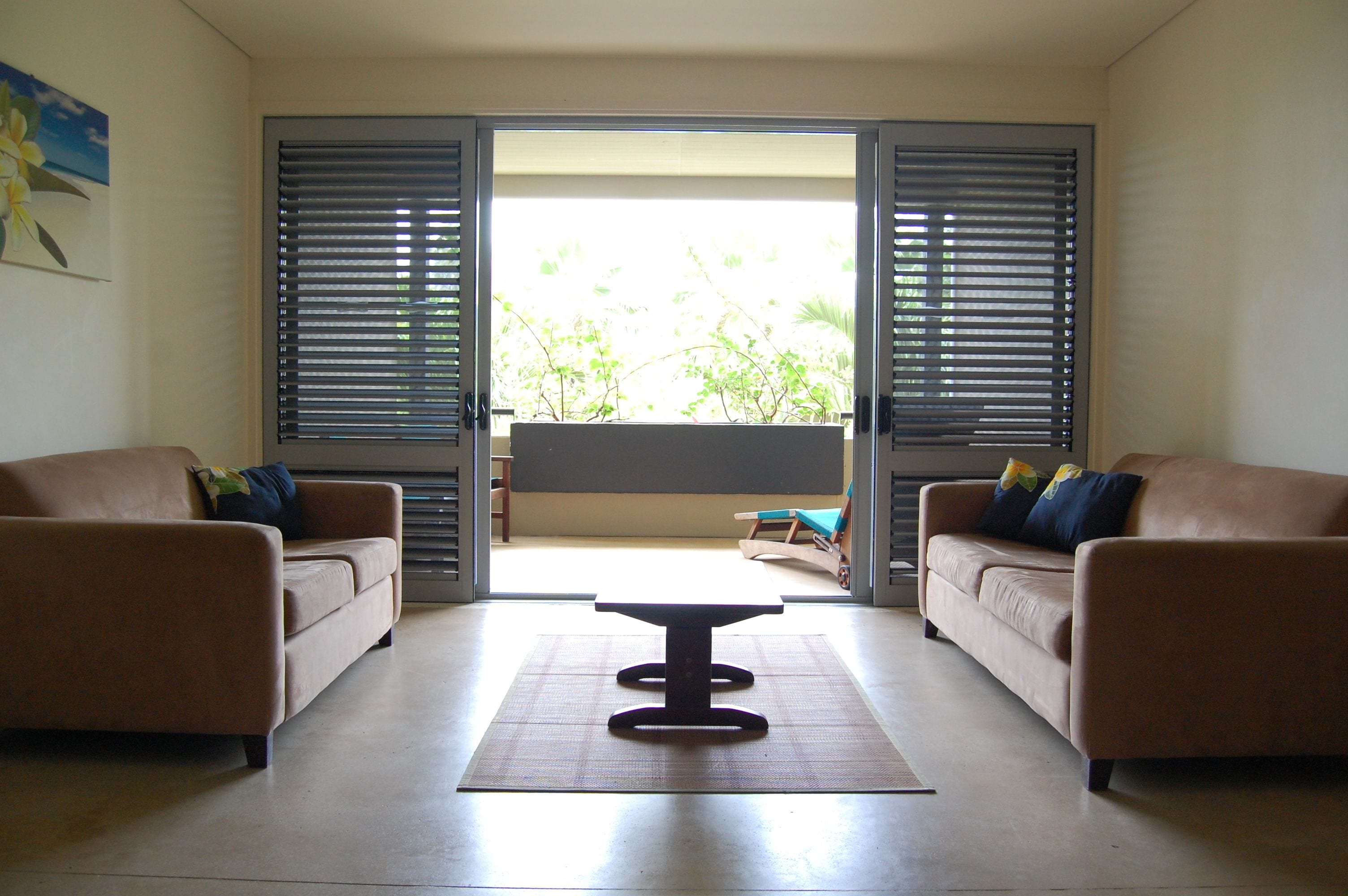 Un salon comprenant deux canapés, une table basse centrale et une porte-fenêtre coulissante donnant sur un balcon.