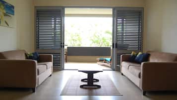 Un salon comprenant deux canapés, une table basse centrale et une porte-fenêtre coulissante donnant sur un balcon.