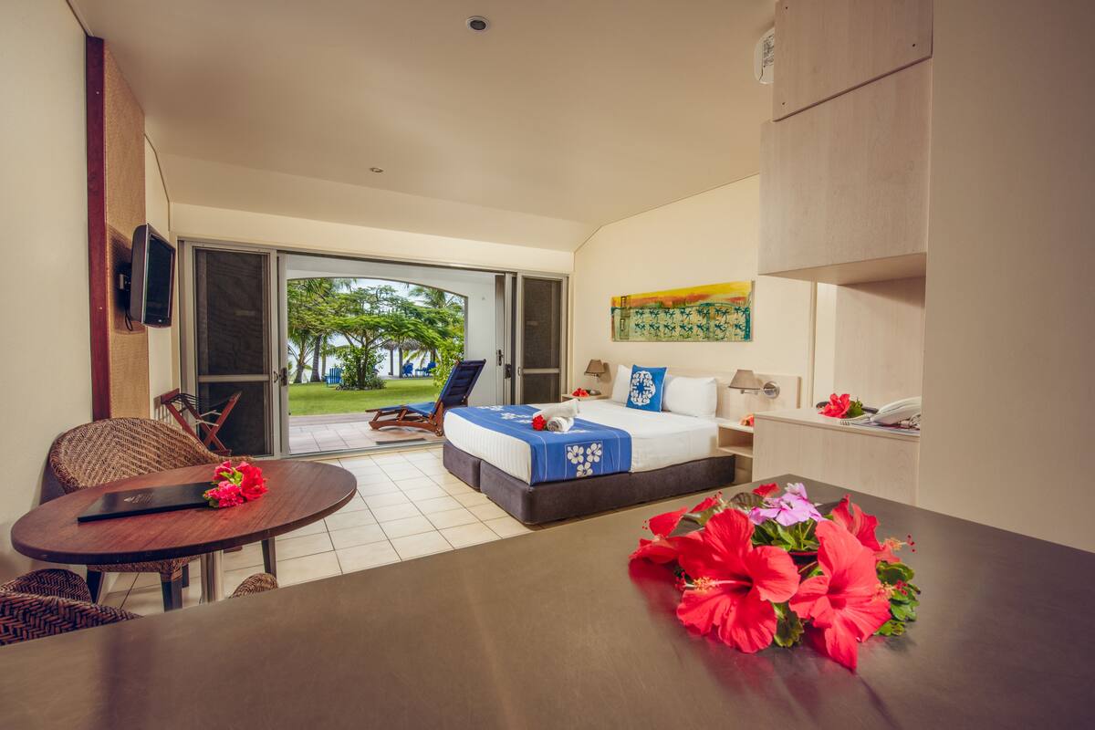 A hotel room with a bed, a desk, a chair, and a view of the outdoors.