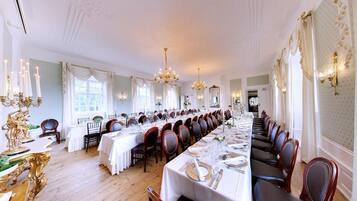 Un comedor formal con mesas largas, candelabros y decoración elegante.