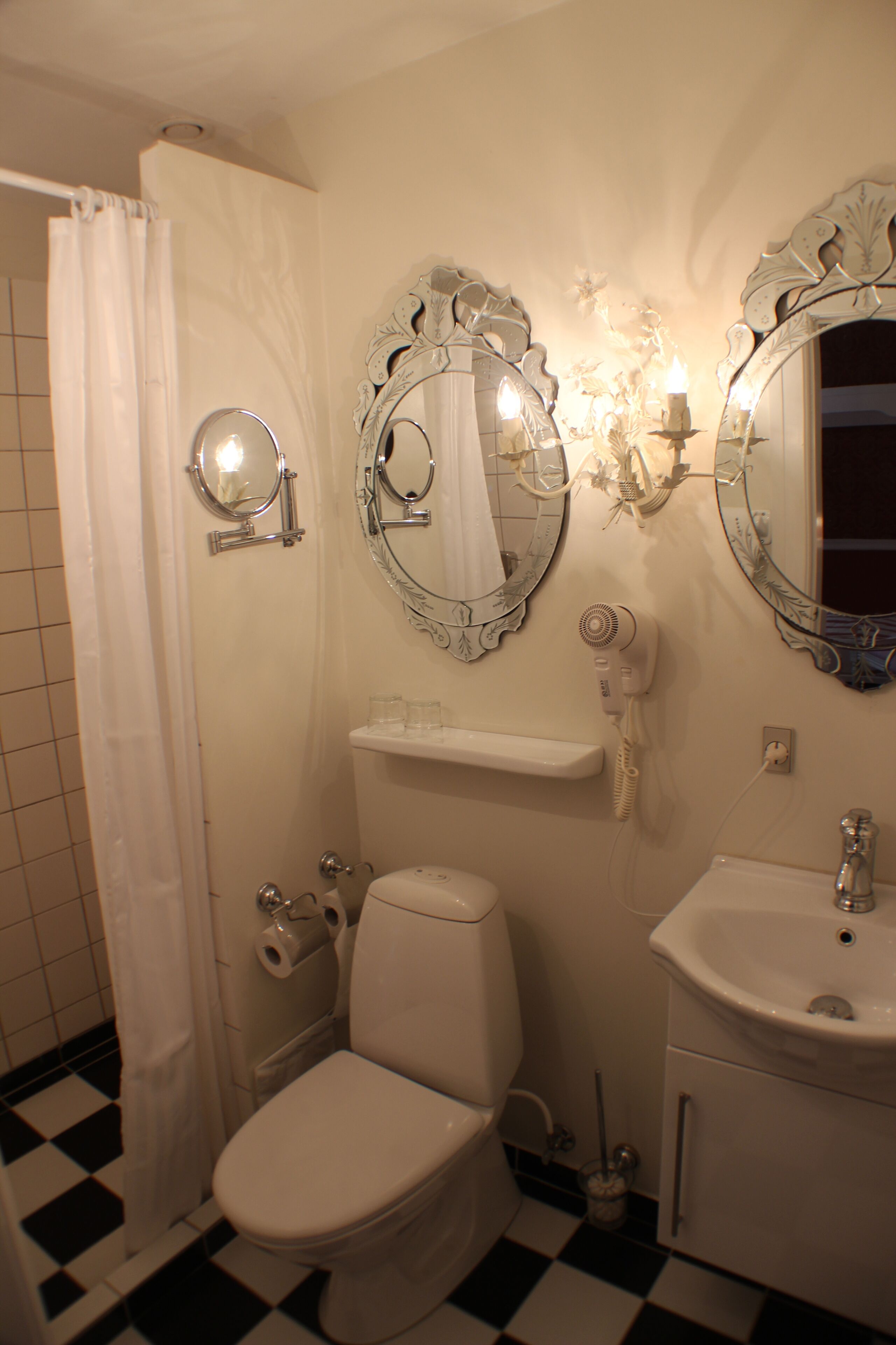 Ein Badezimmer mit Toilette, Waschbecken und zwei verzierten Spiegeln.