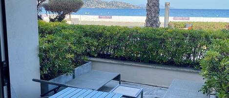 A patio with outdoor furniture, a view of the sea, and a "PARKING DRIVE" sign.